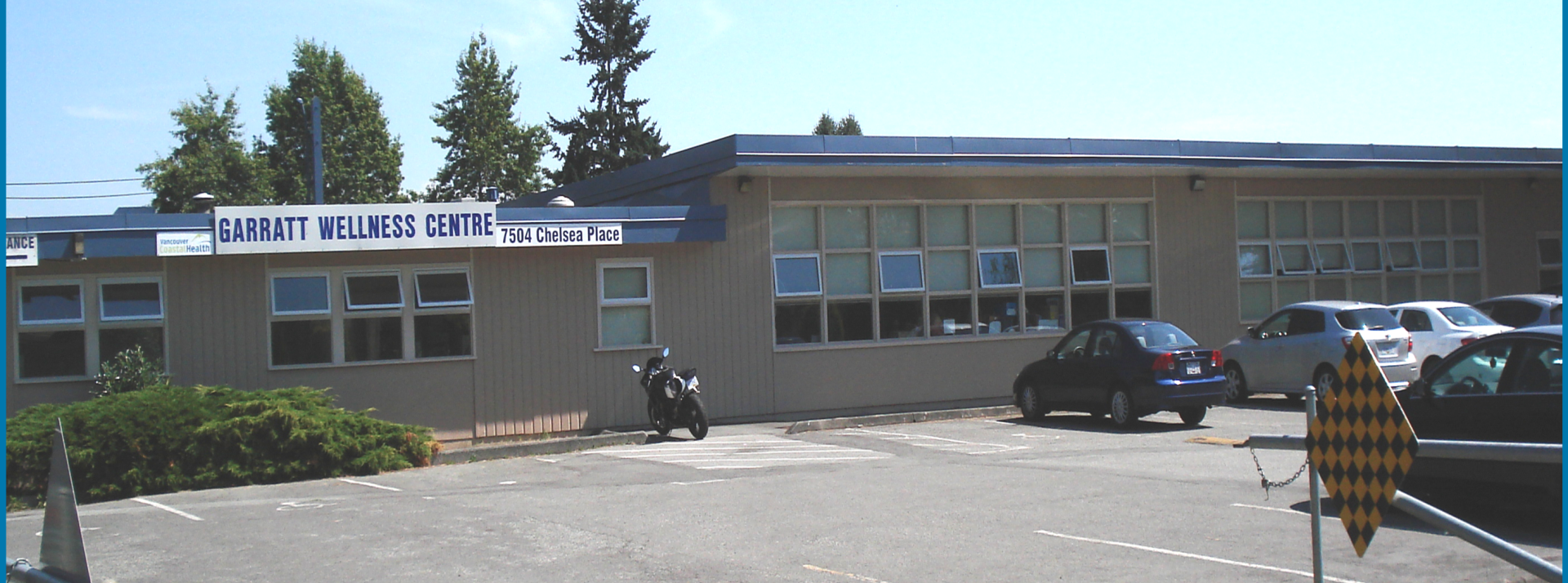 Exterior shot of Garratt Wellness Centre during the day.  The parking lot is visible in the foregound.