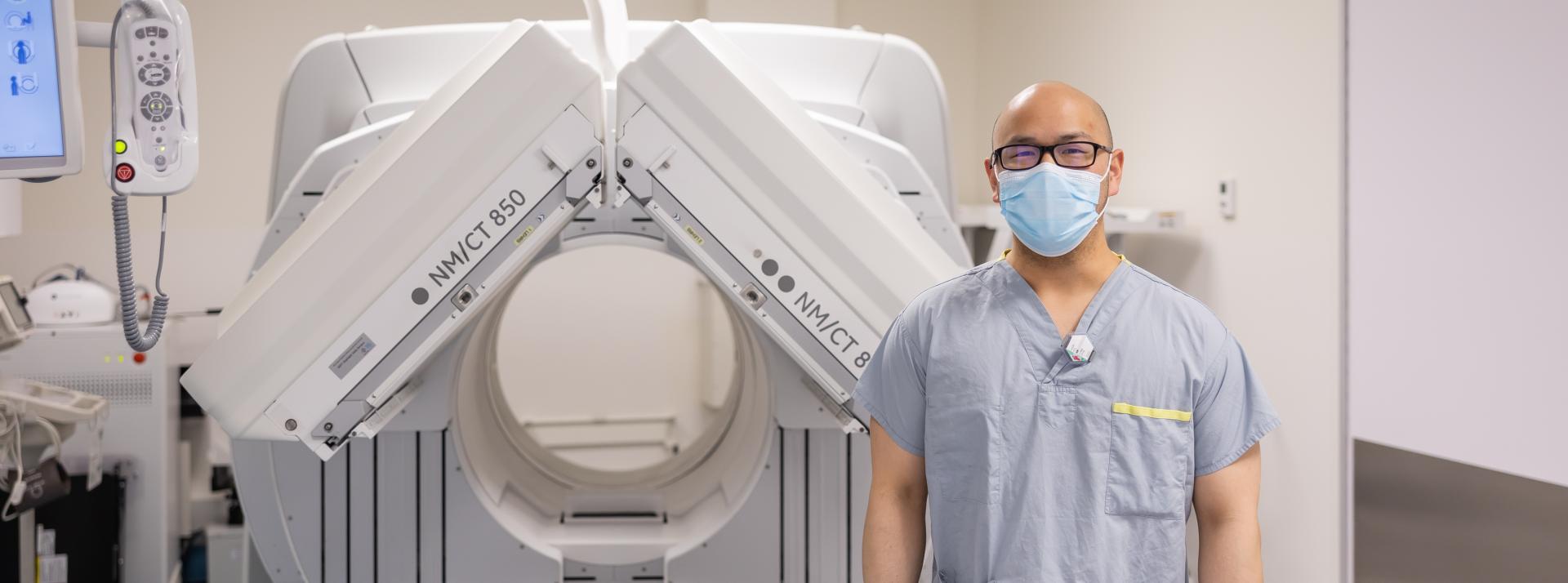 staff stands beside CT machine