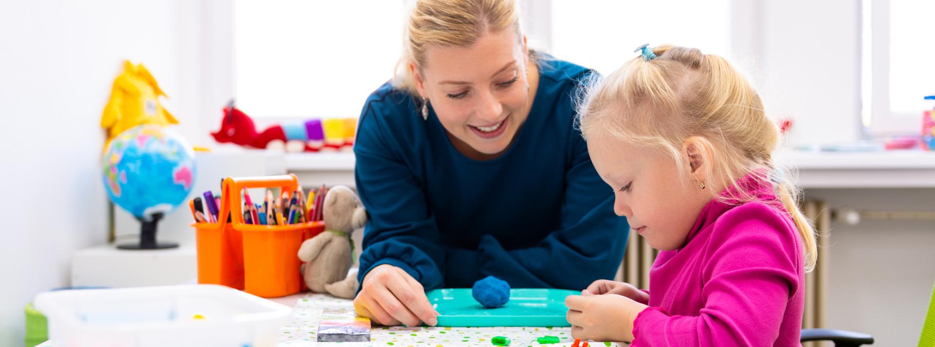 Toddler girl in child occupational therapy session doing sensory playful exercises with her therapist.