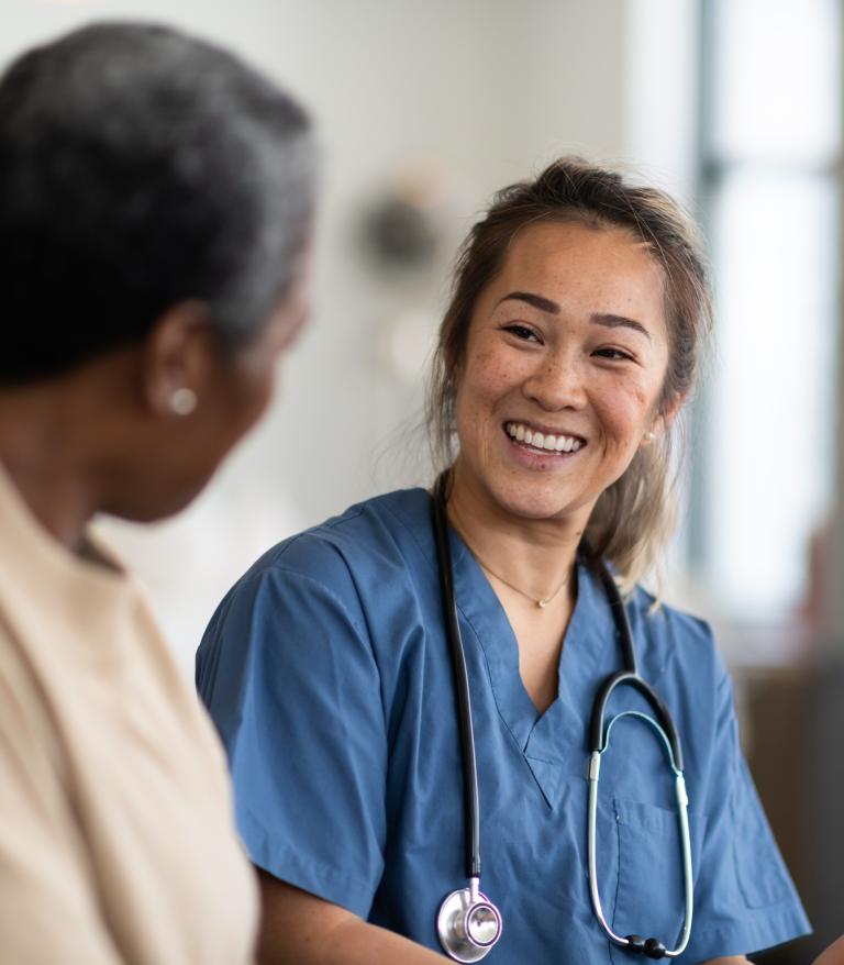 Smiling doctor speaking with patient while reviewing informatio on a clipboard