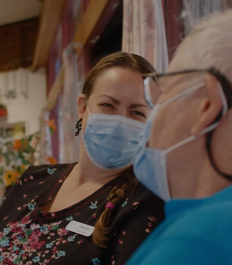A long-term care worker laughing with a resident