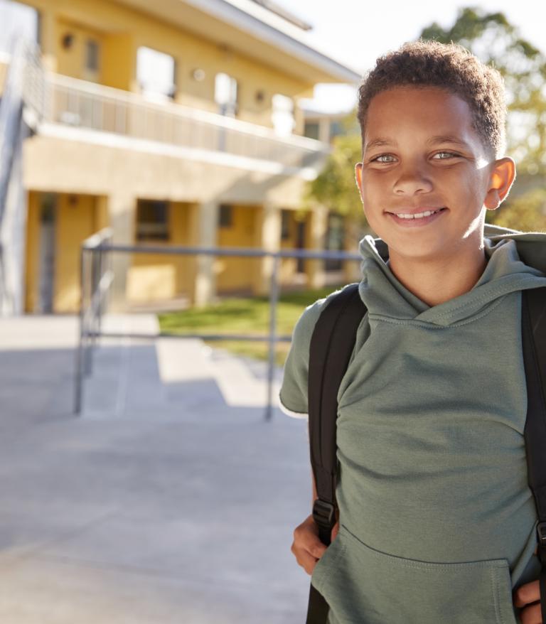 Child smiling outside of a school