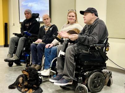 4 people in wheelchairs in a panel at a health forum 
